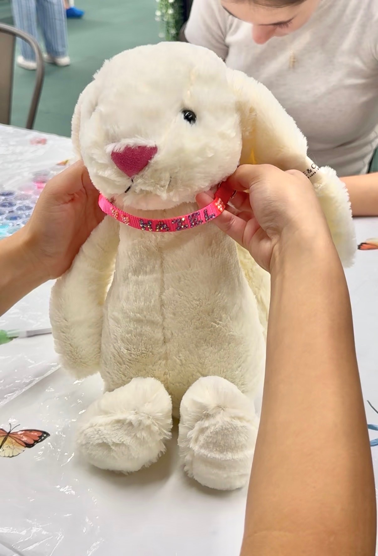 A plush bunny wearing a hand-beaded custom name collar made in the craft room
