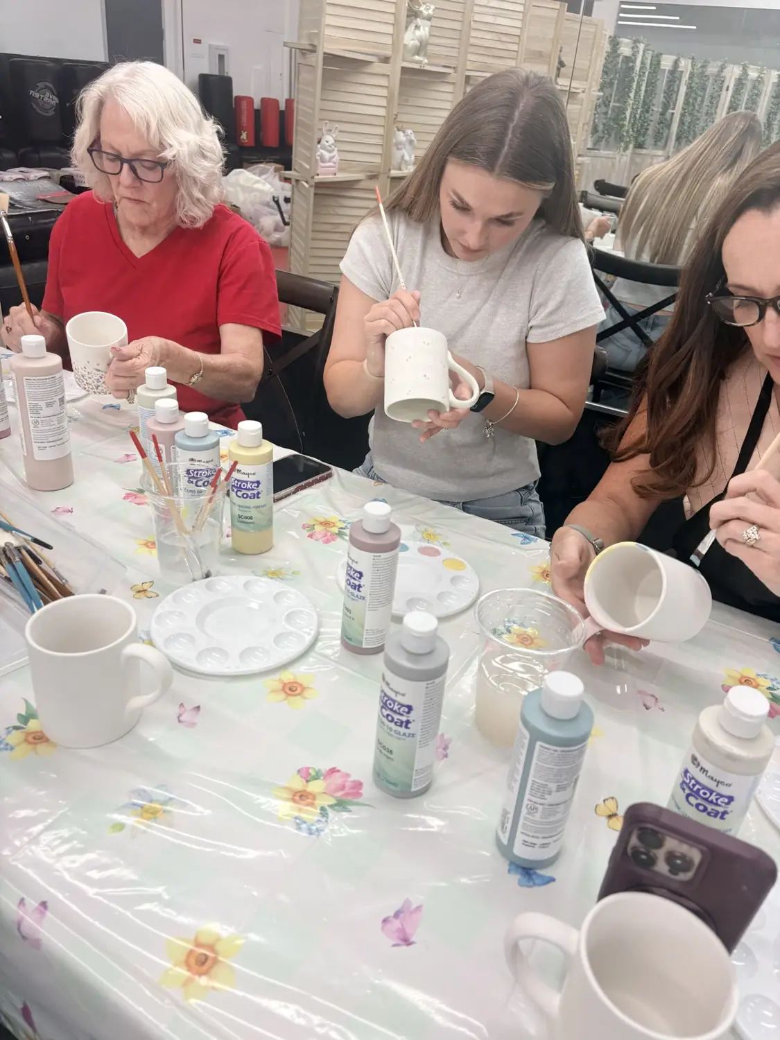 Guests painting ceramic mugs at the craft table