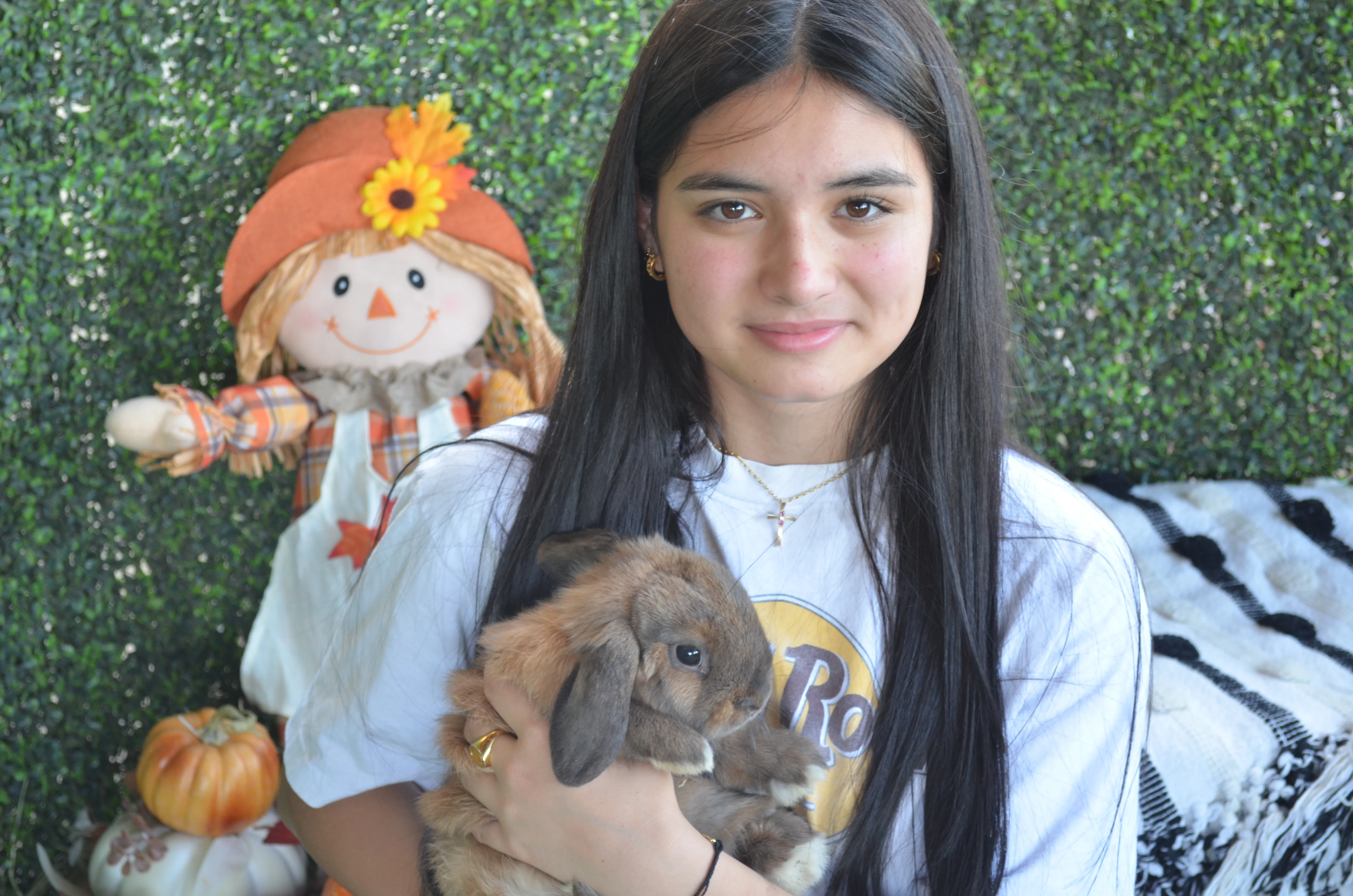 Layla holding a soft lop bunny in front of an autumn-styled set
