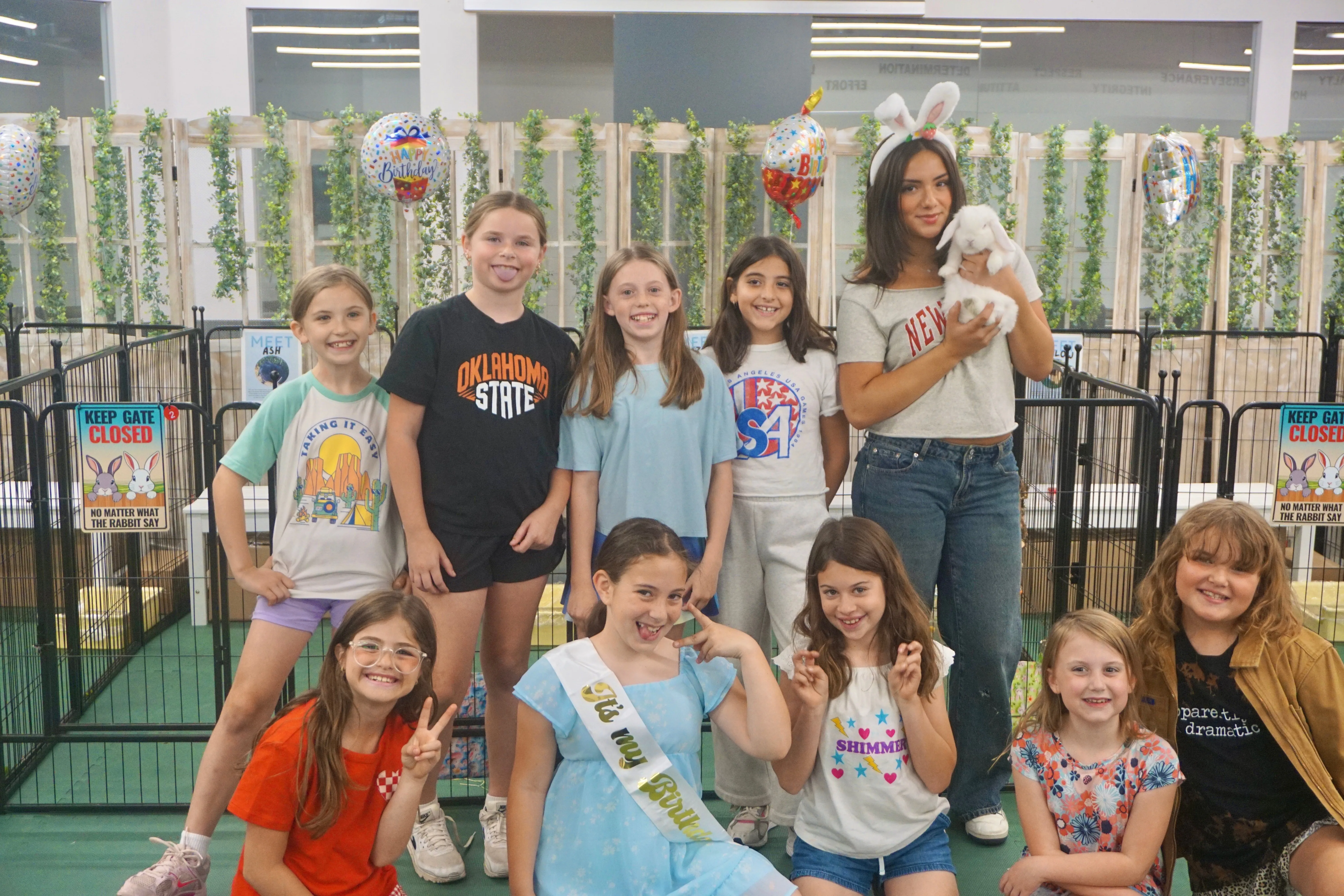 A group of guests posing with bunnies and balloons at a Bunnyville party